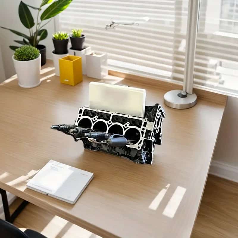 V8 engine model desktop organizer holding pens and business cards on a car dashboard.