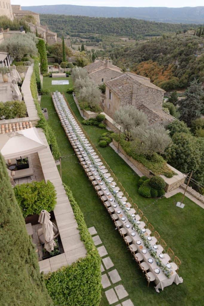 Elegant outdoor banquet setup with long table, white linens, and scenic landscape backdrop for special events.
