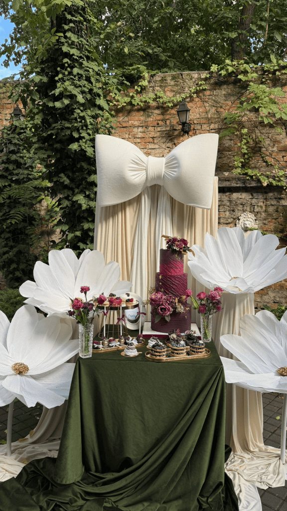 Elegant outdoor wedding dessert table with floral decorations and cake display.