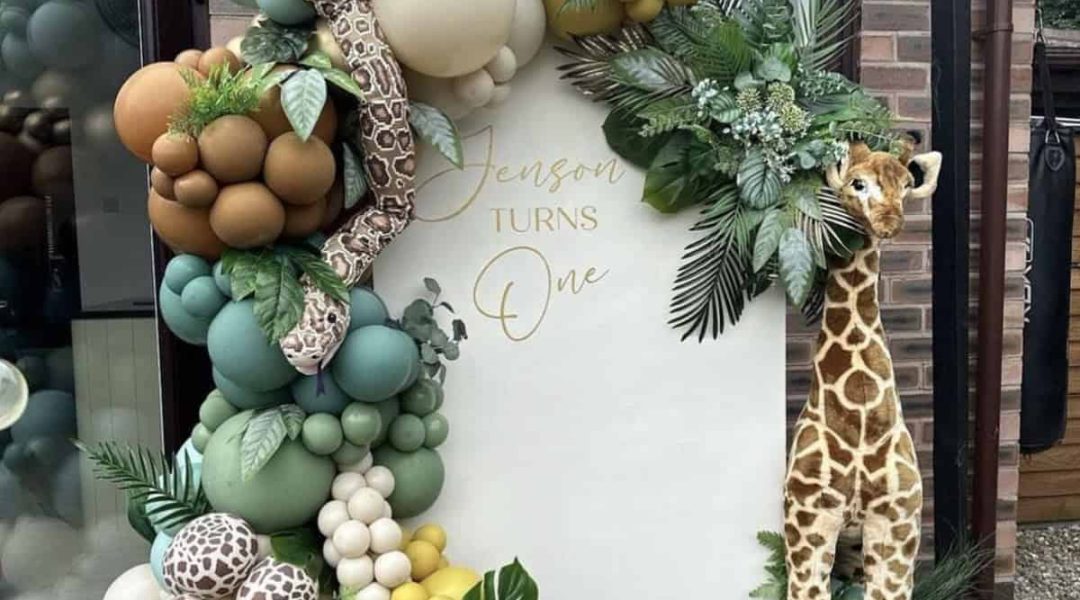 Colorful jungle-themed balloon arch with giraffe and snake decorations, perfect for a children's birthday celebration.