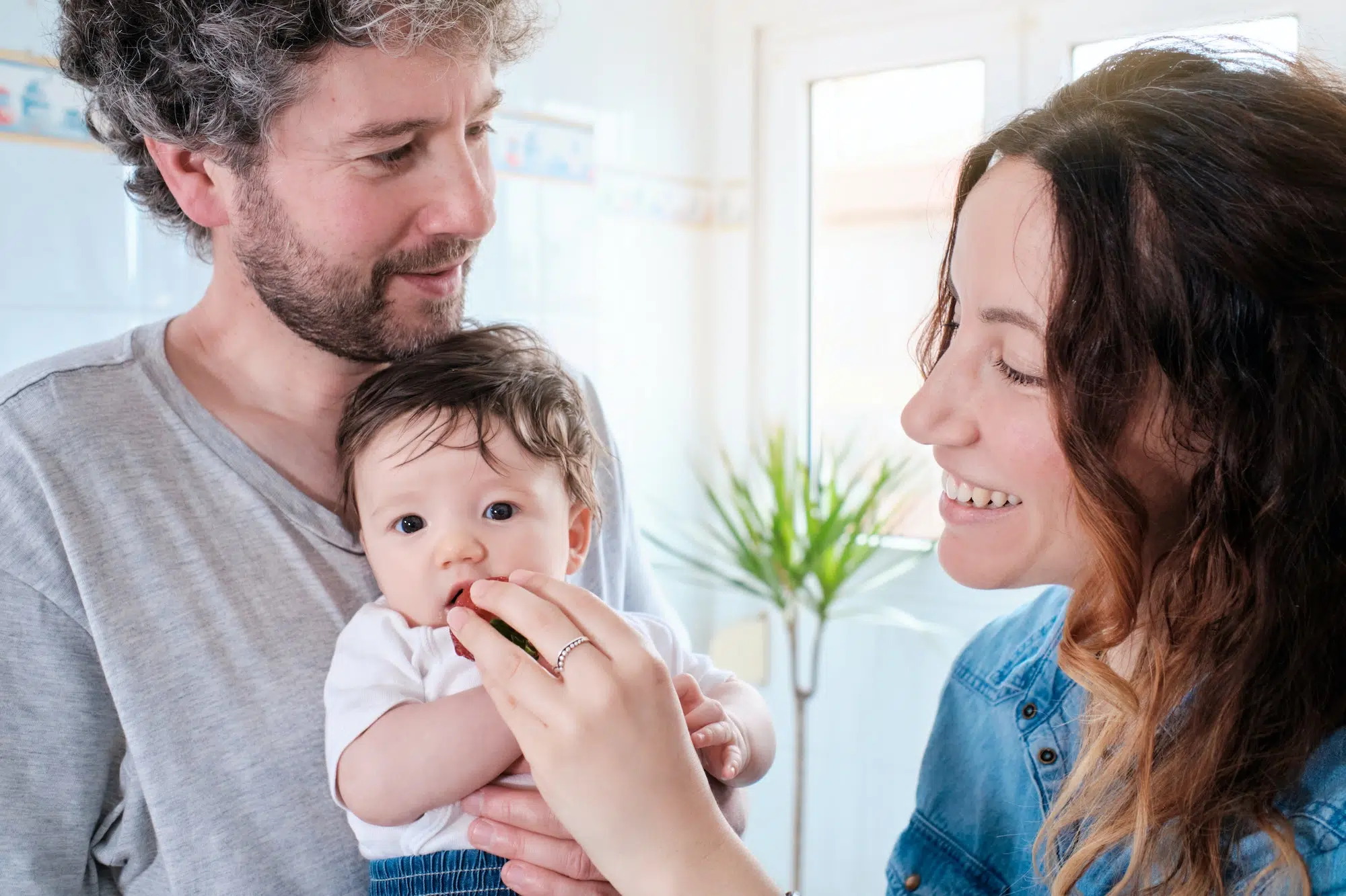 new parents offer solid food to their little baby girl