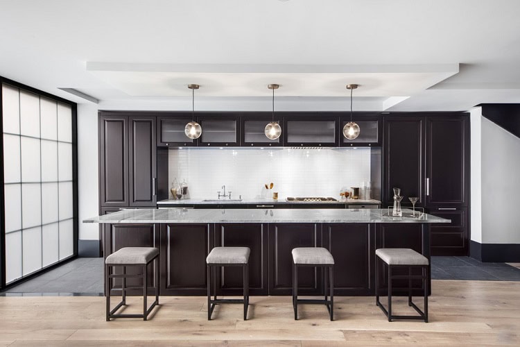 Contemporary urban kitchen featuring dark cabinetry, marble island, and modern pendant lighting.