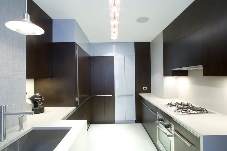 Urban Homes modern kitchen with dark wood cabinets and sleek white countertops, featuring contempora.