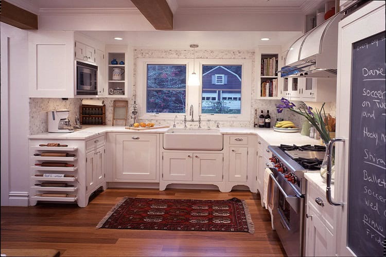 Bright and spacious urban kitchen featuring white cabinetry, a large window, and modern appliances f.