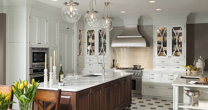 Modern white kitchen with dark island, stainless steel appliances, and elegant lighting fixtures.