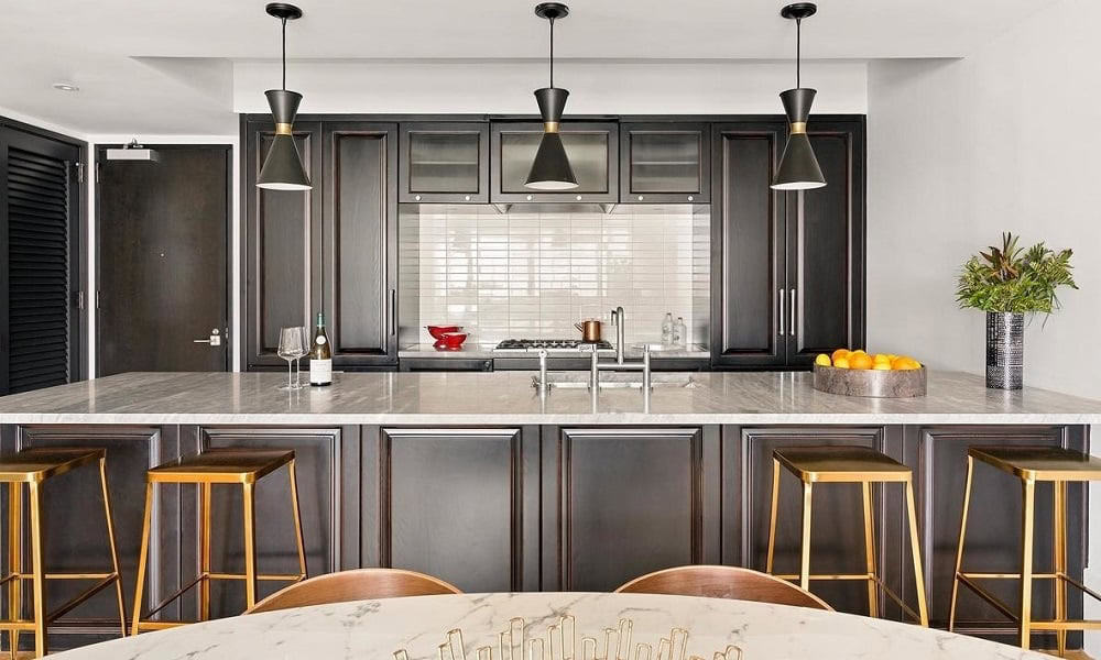 Contemporary urban kitchen featuring dark cabinetry, marble countertops, and stylish pendant lightin.