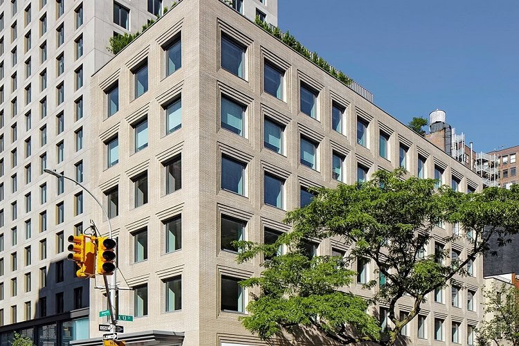 Contemporary urban apartment building with large windows and greenery in a bustling city environment.