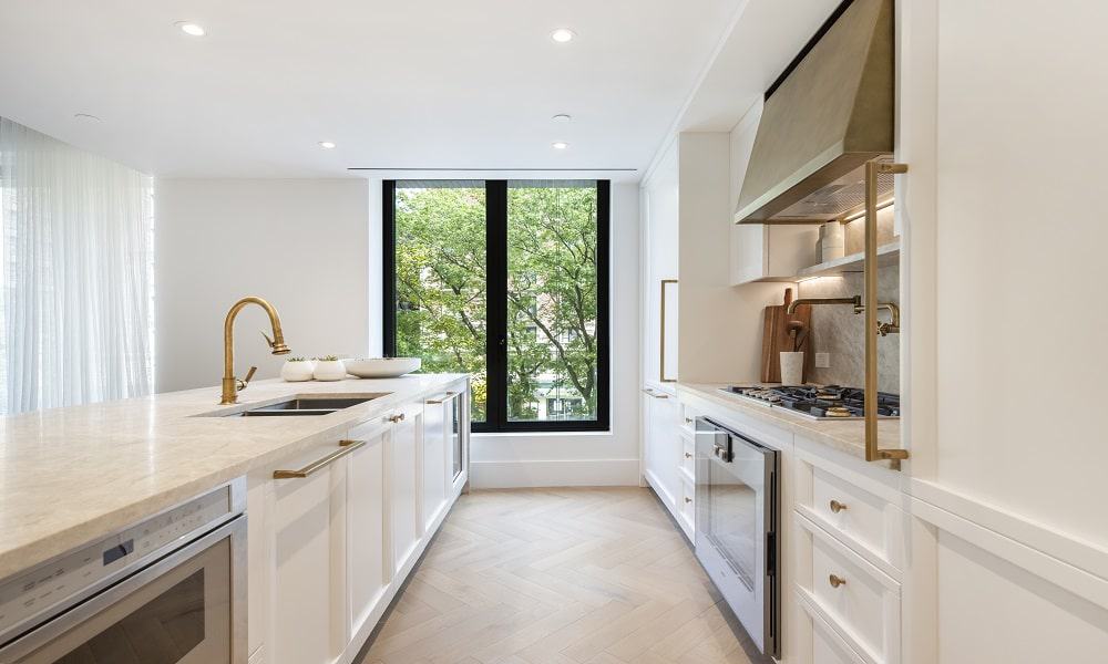 Spacious, bright kitchen featuring white cabinetry, a large window, and modern appliances.