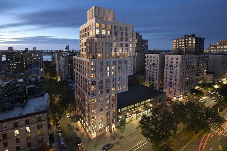 Contemporary multi-unit apartment building in an urban setting at dusk.