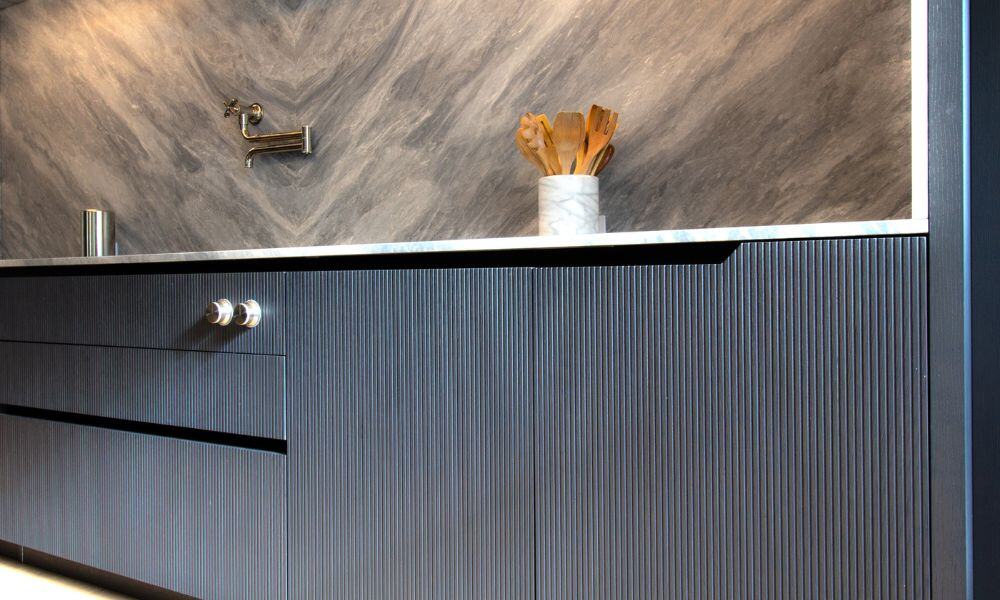 Elegant kitchen cabinetry with sleek gray drawers and a marble backsplash.