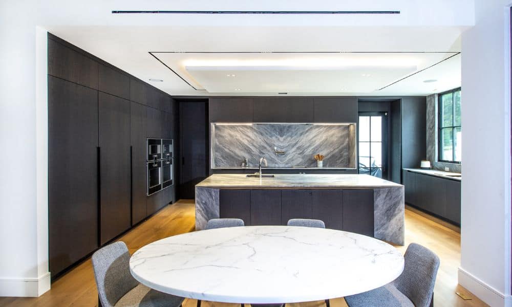 Contemporary kitchen featuring a marble island, dark cabinetry, and large windows for natural light.
