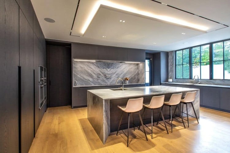 Modern kitchen in New Jersey with dark wood cabinetry, marble waterfall island, and wide-plank oak flooring