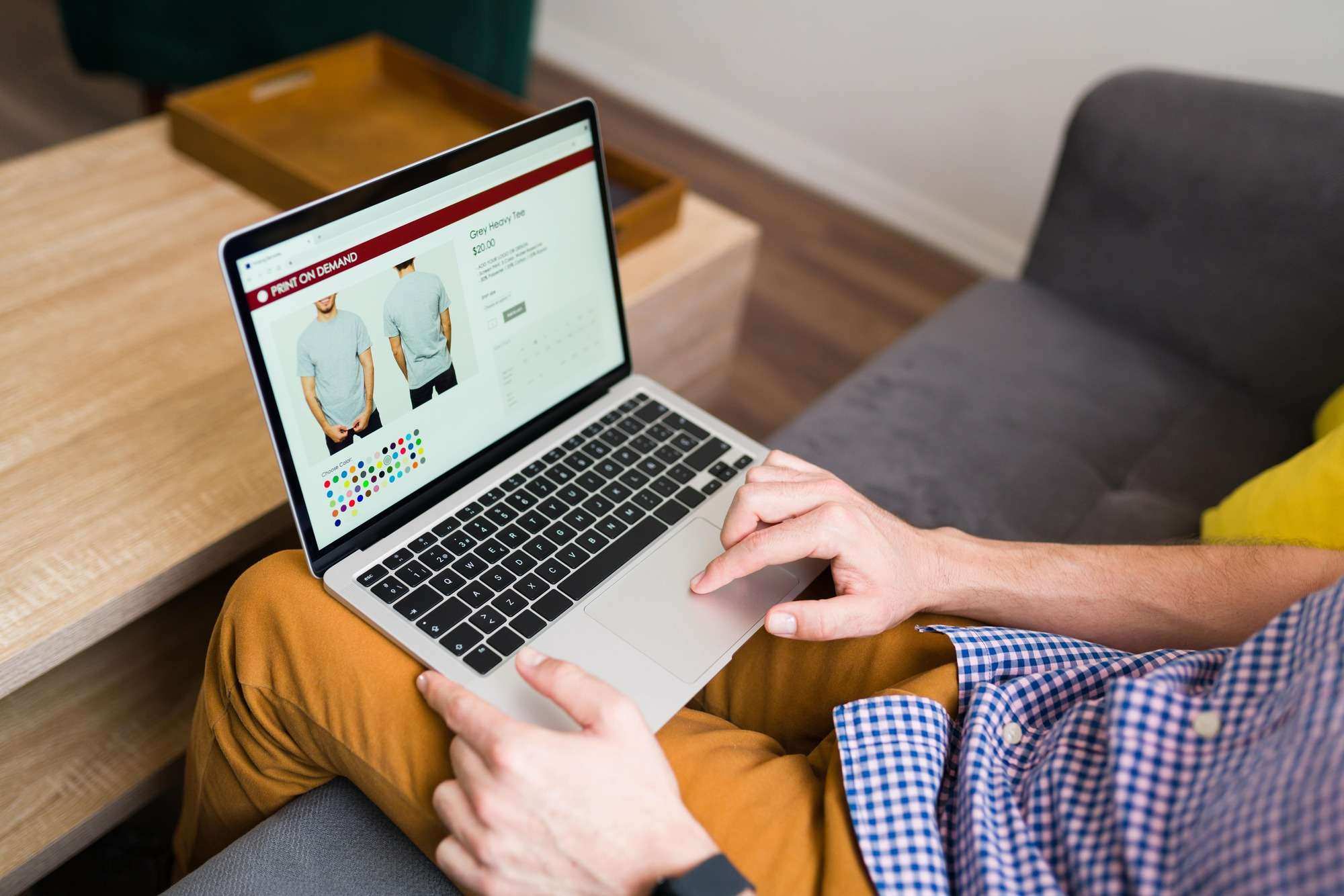 Férfi laptopon vásárol egy nyomtatási rendszeren keresztül pólót.