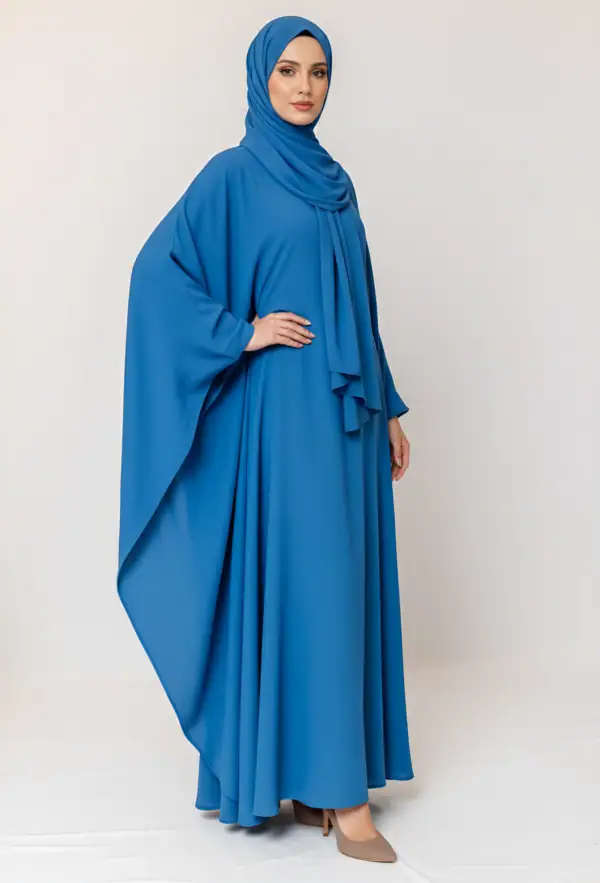 Woman wearing a flowing blue abaya and matching hijab, full-length portrait.