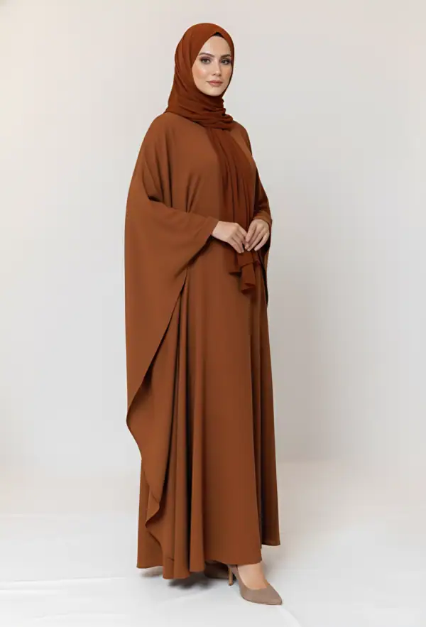 Woman wearing a stylish brown abaya and matching hijab, standing confidently.