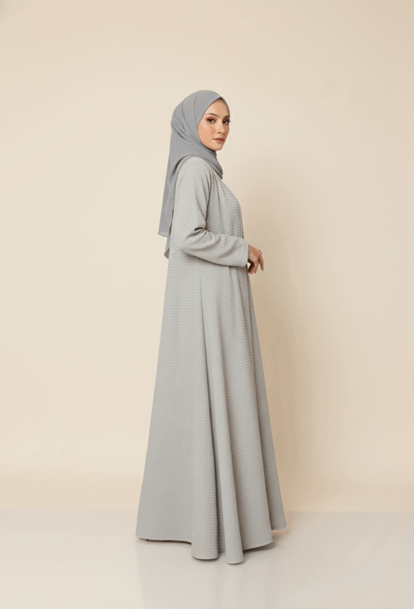 Elegant Muslim woman in a modest grey abaya and hijab, showcasing contemporary Islamic fashion.