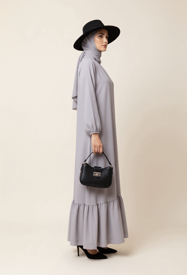 Elegant Muslim woman in modest grey dress with hijab, black hat, and handbag, showcasing contemporar.