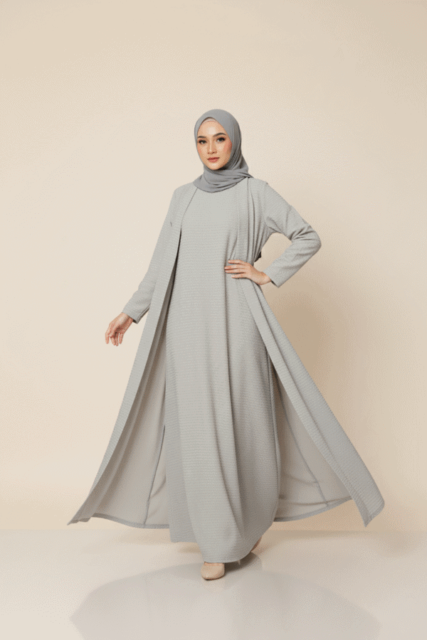 Woman wearing a stylish, modest grey dress with a matching hijab, showcasing contemporary fashion.