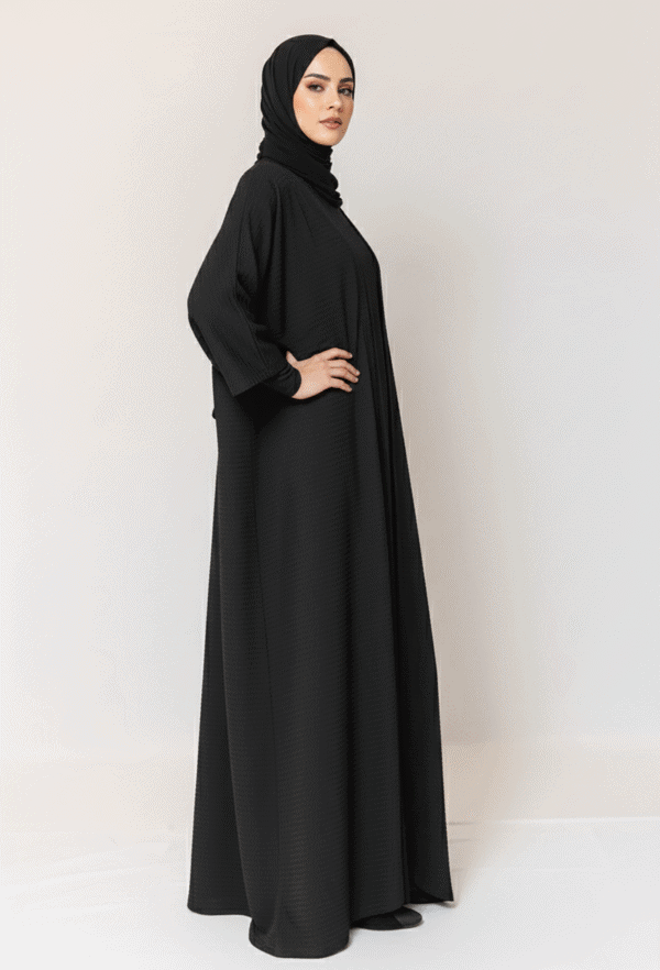Woman wearing a stylish black abaya and hijab, showcasing modest Islamic fashion.