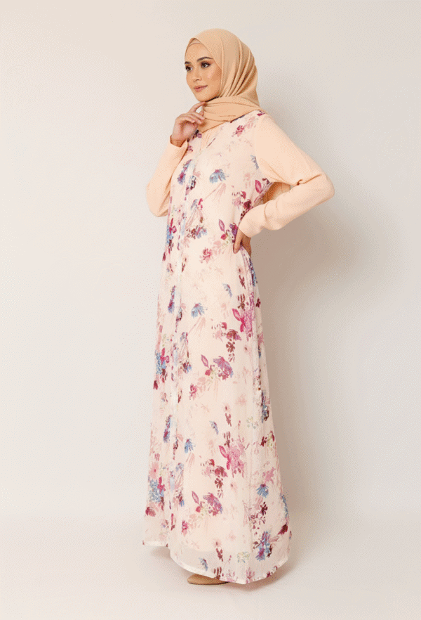 Elegant woman in floral maxi dress with beige hijab, showcasing modest fashion and contemporary styl.