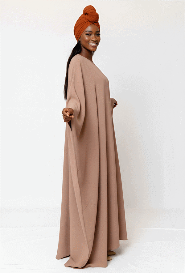 Beautiful woman in beige modest dress with orange headwrap, promoting stylish, conservative clothing.