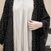 Close-up of modest fashion dress featuring pleated white fabric with a black polka dot outer layer, stylish and comfortable for women.