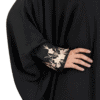Elegant black abaya with intricate gold embroidery on sleeve, showcasing traditional Islamic fashion.
