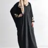 Woman wearing a stylish black abaya with intricate embroidery on sleeves.