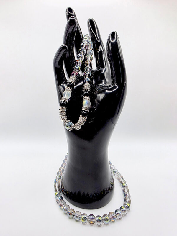 Beaded jewelry displayed on a glossy black hand mannequin, showcasing necklaces and bracelets with c.