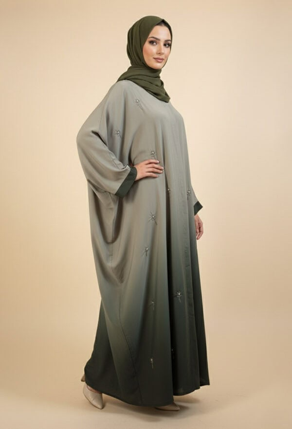 Woman wearing a stylish, modest abaya with embroidery and a green hijab.