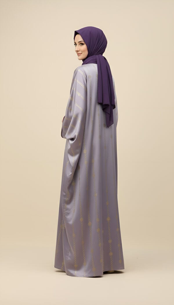 Woman in purple hijab and silver abaya with gold details, standing sideways.
