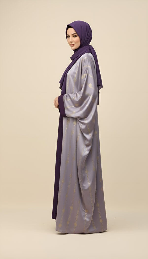 Woman wearing a purple and gold embroidered abaya with matching hijab, standing sideways.