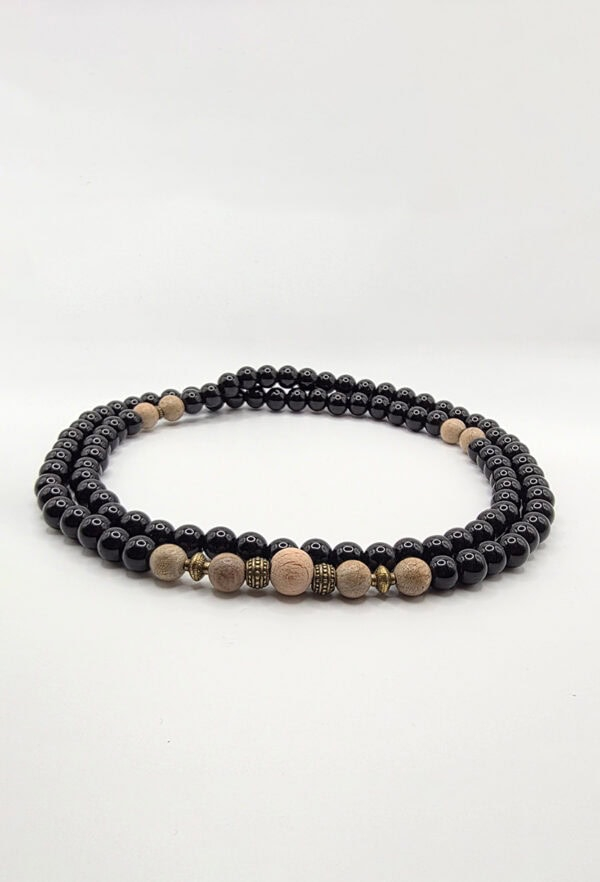 Stylish black beaded necklace with beige and metallic accents for versatile fashion.