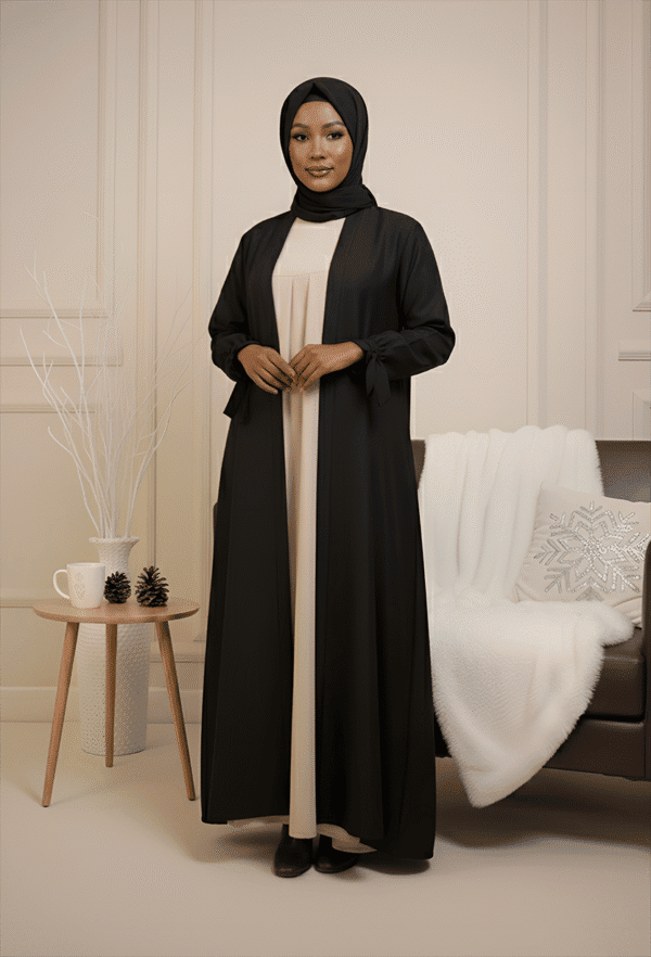 Beautiful woman wearing stylish modest black abaya and hijab, indoor setting.