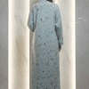 Woman in a light blue embroidered dress standing with her back to the camera.