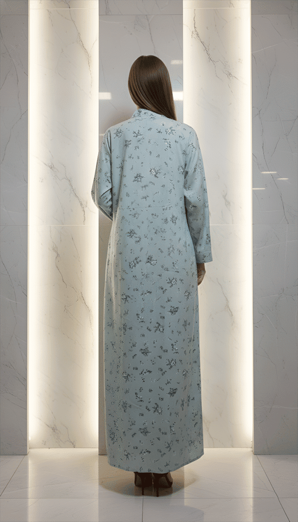 Woman in a light blue embroidered dress standing with her back to the camera.