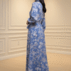 Woman in a blue floral maxi dress standing indoors, showcasing stylish fashion.