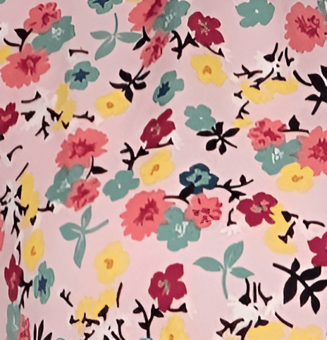 Pink floral fabric with colorful flowers and black accents, perfect for fashion or home decor projec.