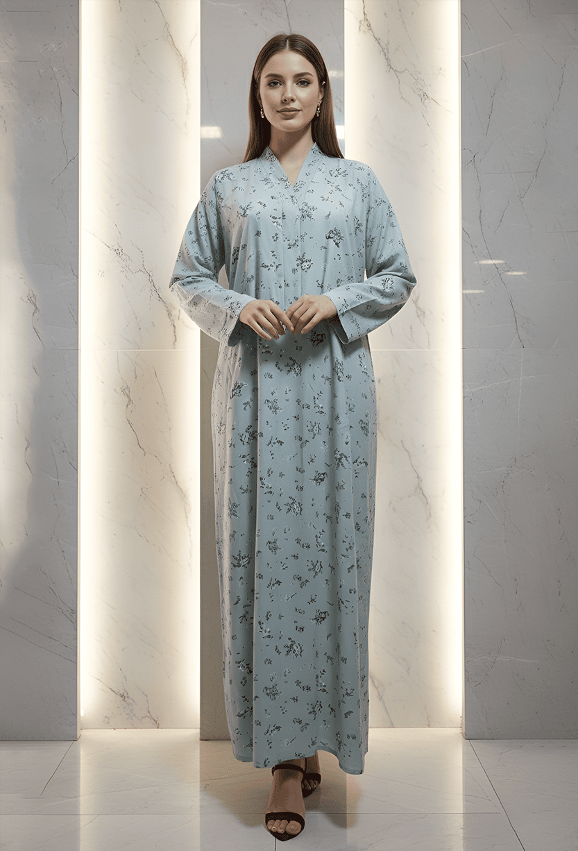 Woman in light blue embroidered dress standing against marble wall.