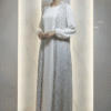 Woman wearing a stylish white abaya with intricate embroidery, standing confidently indoors.