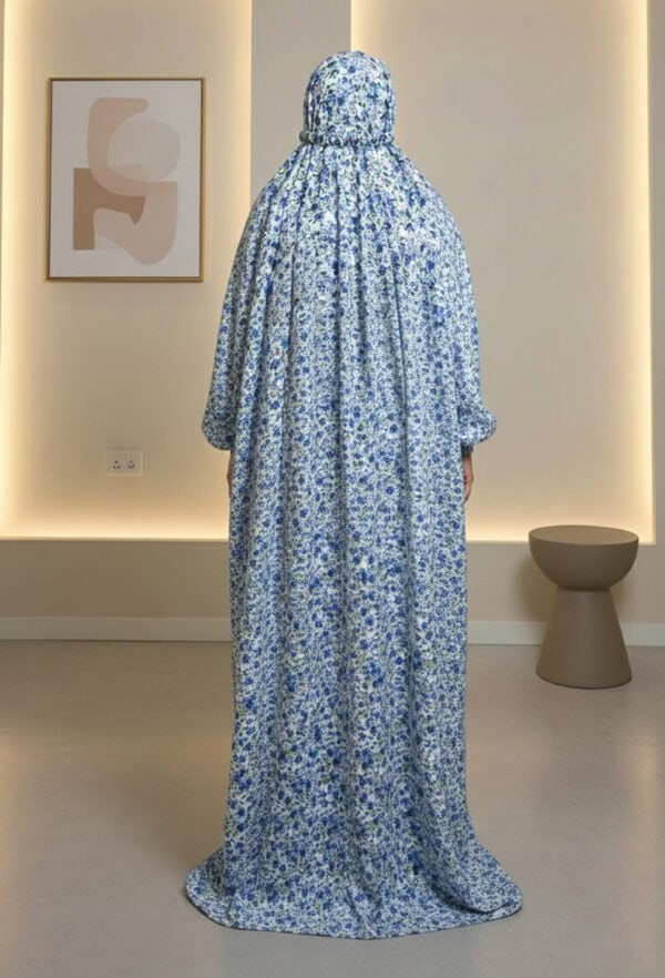 Mannequin wearing a long, floral printed dress with a matching headscarf, displayed in a modern gall.