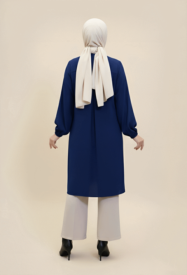 Woman in modest blue coat and white hijab, full back view.