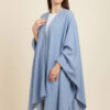 Woman wearing a stylish light blue cape with a relaxed fit.