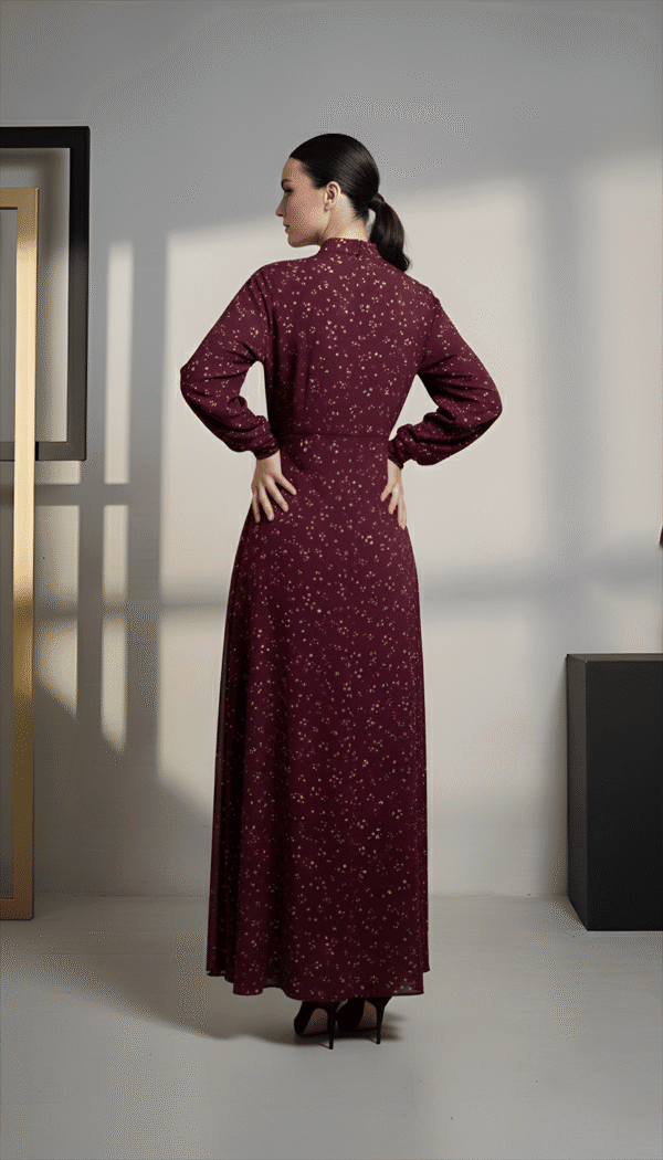 Woman wearing a maroon embroidered dress with long sleeves and a flowing skirt, standing indoors.