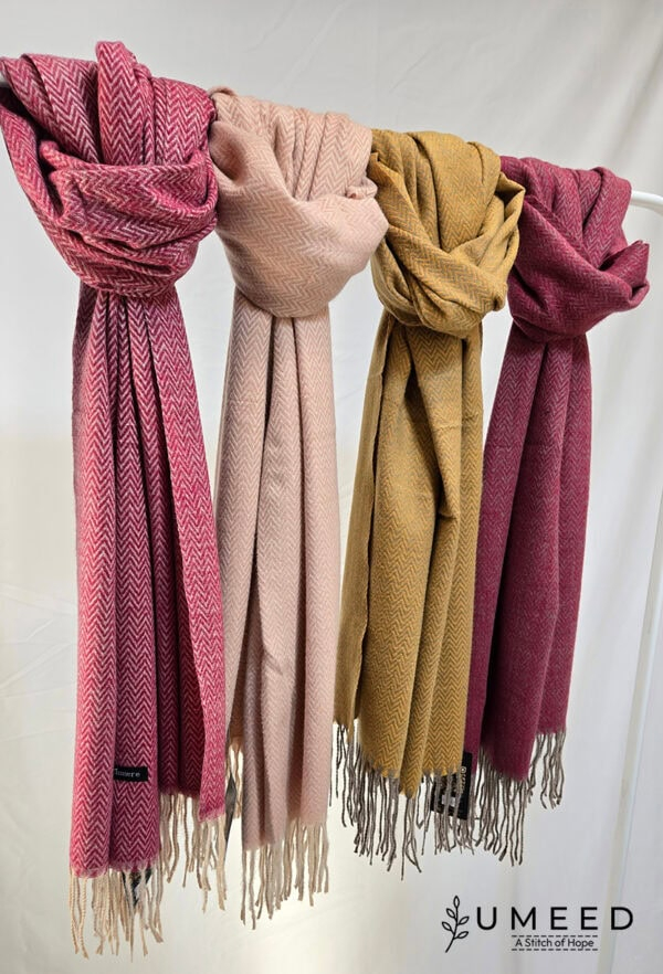 Elegant wool scarves in pink, beige, mustard, and maroon hanging on a rack. Perfect for stylish wint.