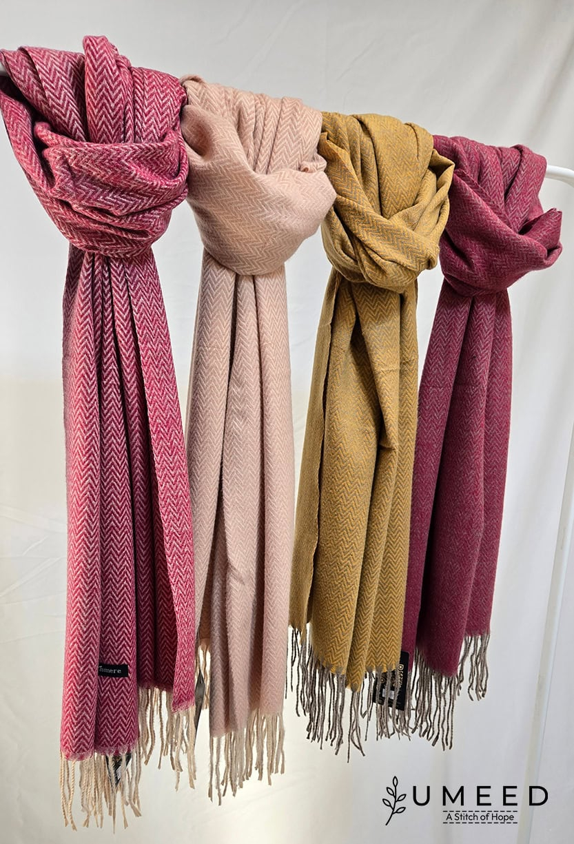 Elegant wool scarves in pink, beige, mustard, and maroon hanging on a rack. Perfect for stylish wint.