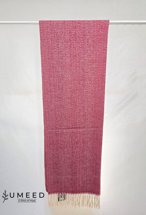 Handwoven pink and white textile scarf displayed on a white background.