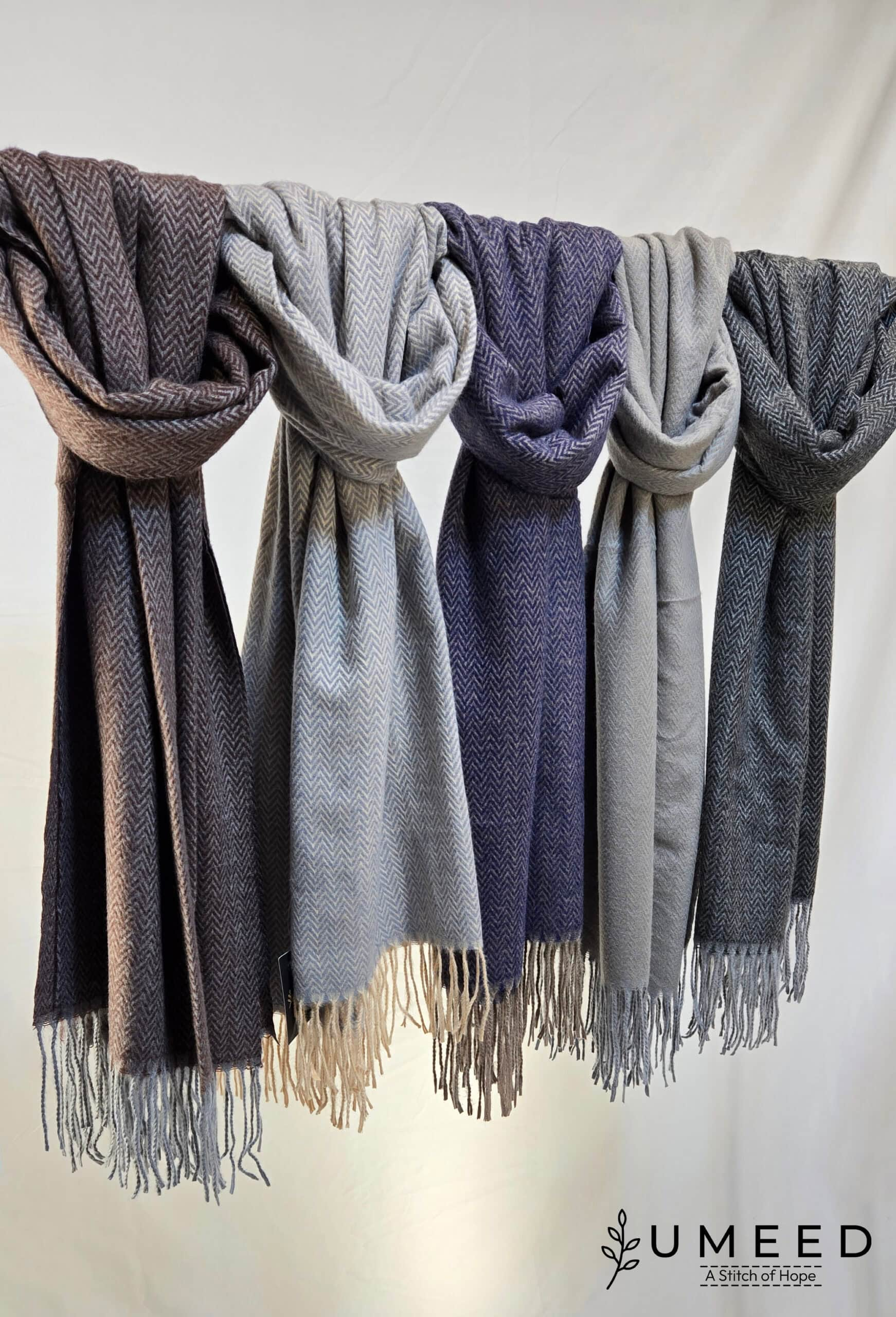 Wool scarves in gray, blue, and beige tones displayed on a hanger.