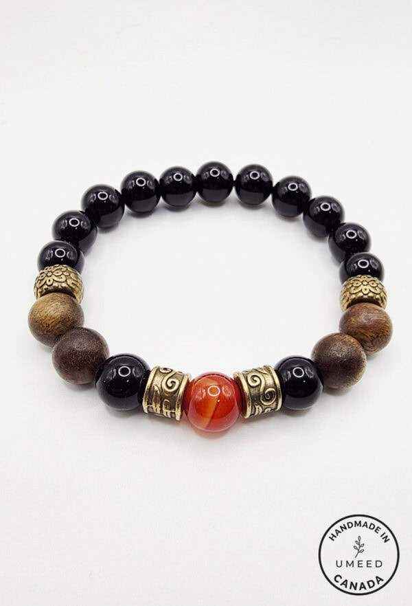 Handmade beaded bracelet featuring black, brown, and gold beads with a central red stone, crafted in.