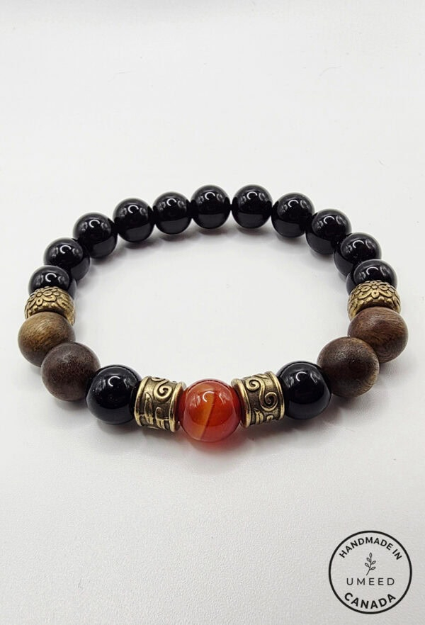 Bracelet featuring black, brown, and gold beads with a central orange bead. Handmade jewelry from Um.